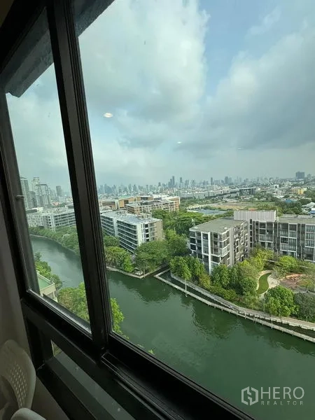公寓 出租或出售 - 高楼窗外可见运河、绿地与曼谷天际线。