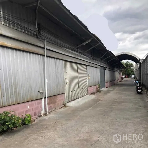 货栈 出租在Khan Na Yao, Bangkok - 金属板外墙的仓库外观，卷帘门沿约5米宽通道分布。