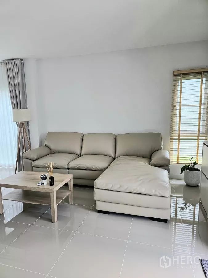 Detached House for rent in Bang Phli, Samut Prakan - Beige L-shaped leather sofa with coffee table beside the window.