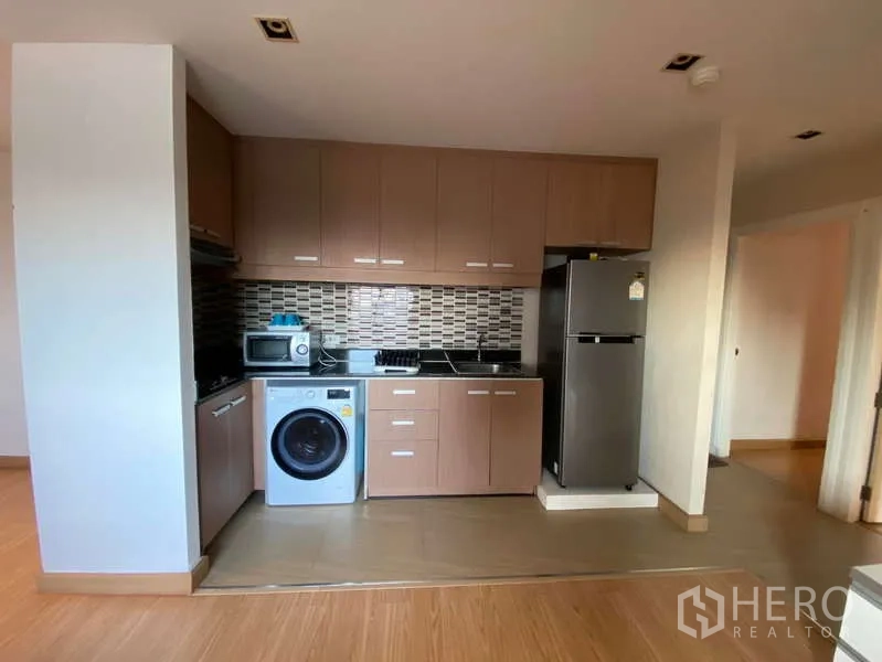 公寓 出租在Khlong Toei, Bangkok - 开放式厨房，木色橱柜与马赛克墙砖，配灶台、微波炉、冰箱和洗衣机。