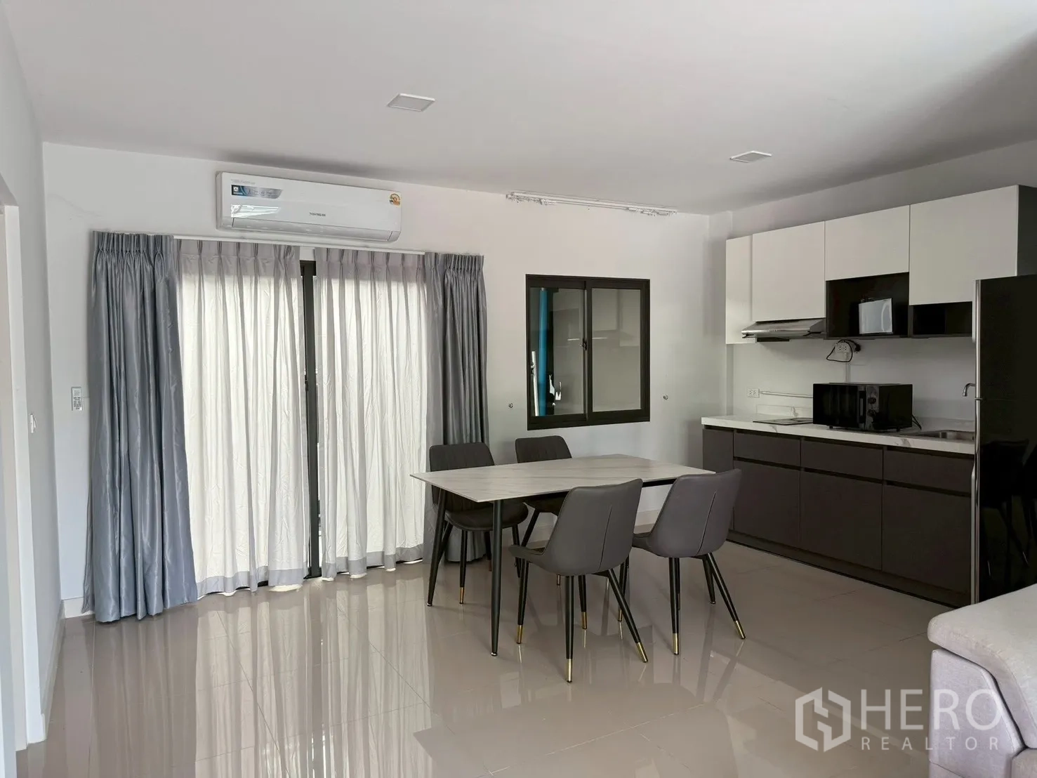 Townhouse for rent in Bang Phli, Samut Prakan - Open-plan kitchen and dining area with table, cabinets, microwave and fridge.