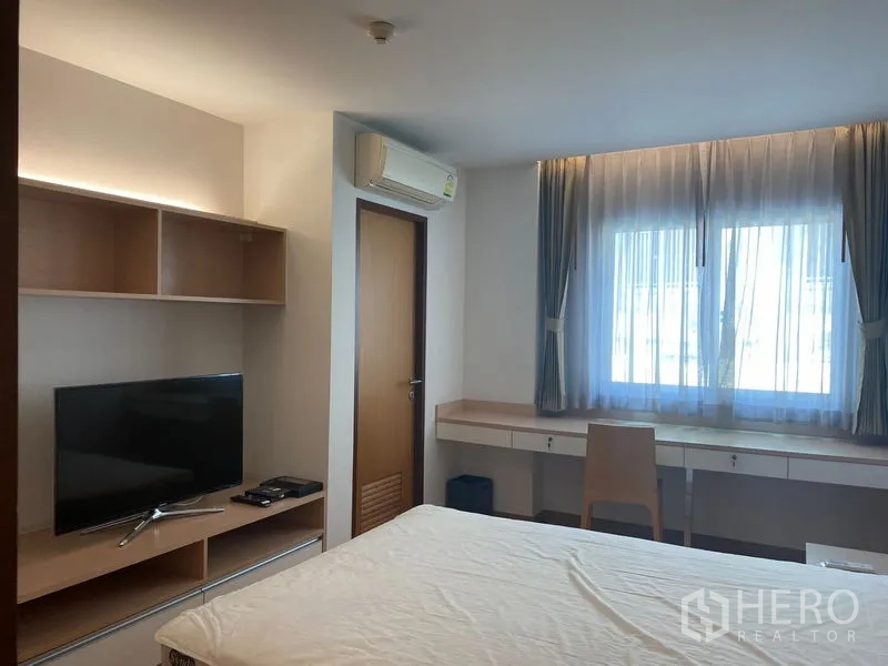 คอนโด ให้เช่าหรือขายในKhlong Toei, Bangkok - ห้องนอนมีทีวีและชั้นวางของ พร้อมแอร์และโต๊ะทำงานยาวริมหน้าต่าง