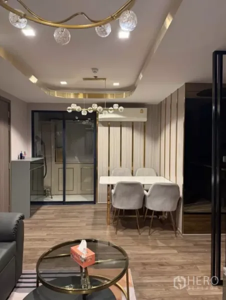 Condominium for rent in Chatuchak, Bangkok - Open-plan dining area with marble table, four upholstered chairs, glass partition, and modern ceiling lights.