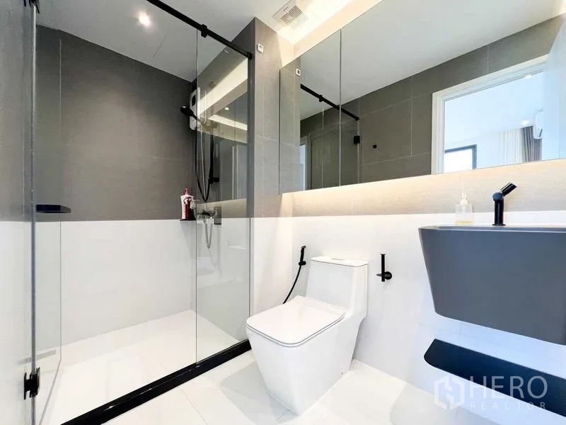 Condominium for rent or sale - Bathroom with glass-enclosed shower, wall-mounted vanity and matte black fixtures.