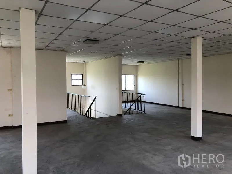 Shophouse for sale in Lam Luk Ka, Pathum Thani - Expansive upper level with structural columns and multiple windows overlooking greenery.