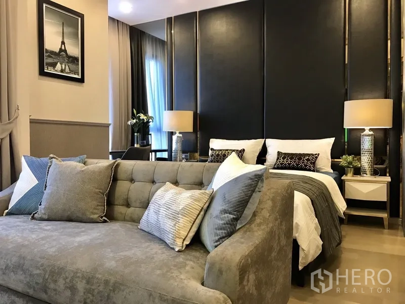 คอนโด ให้เช่าในWatthana, Bangkok - โซนนอนแบบสตูดิโอ ผนังตกแต่งสีเข้ม โคมไฟตั้งโต๊ะ และโซฟาบุผ้า