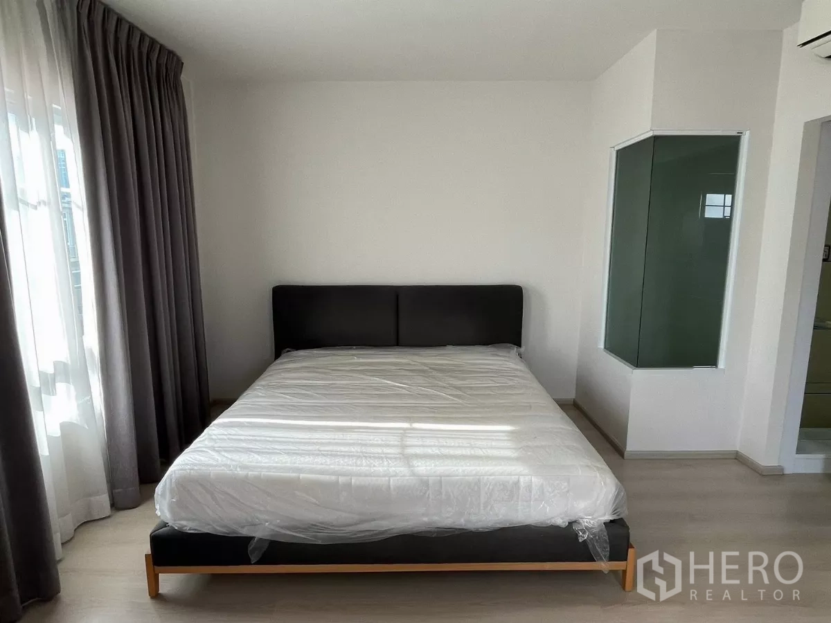 Townhouse for rent in Bang Phli, Samut Prakan - Bedroom with double bed, sheer drapes and glass-walled ensuite shower.