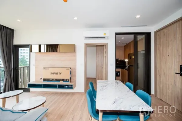 คอนโด ให้เช่าในWatthana, Bangkok - ผนังทีวีและพื้นที่ทานอาหารหันสู่ระเบียง มีประตูบานเลื่อนไปยังครัวปิด