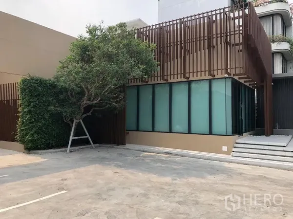 零售空间 出租在Watthana, Bangkok - 现代低层商铺外观，磨砂玻璃立面与竖向格栅，前方设有宽阔停车区。