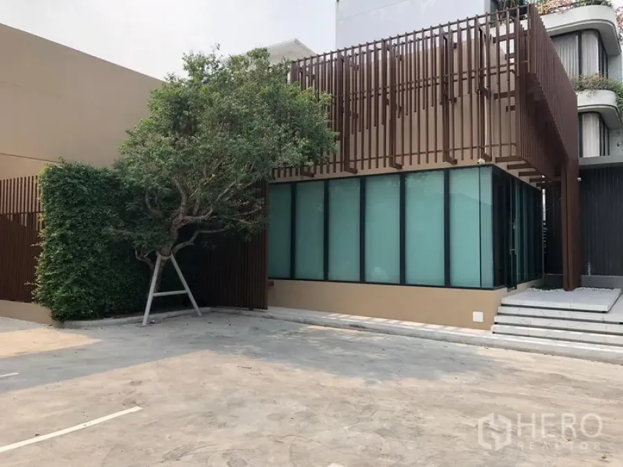 零售空间 出租在Watthana, Bangkok - 现代低层商铺外观，磨砂玻璃立面与竖向格栅，前方设有宽阔停车区。