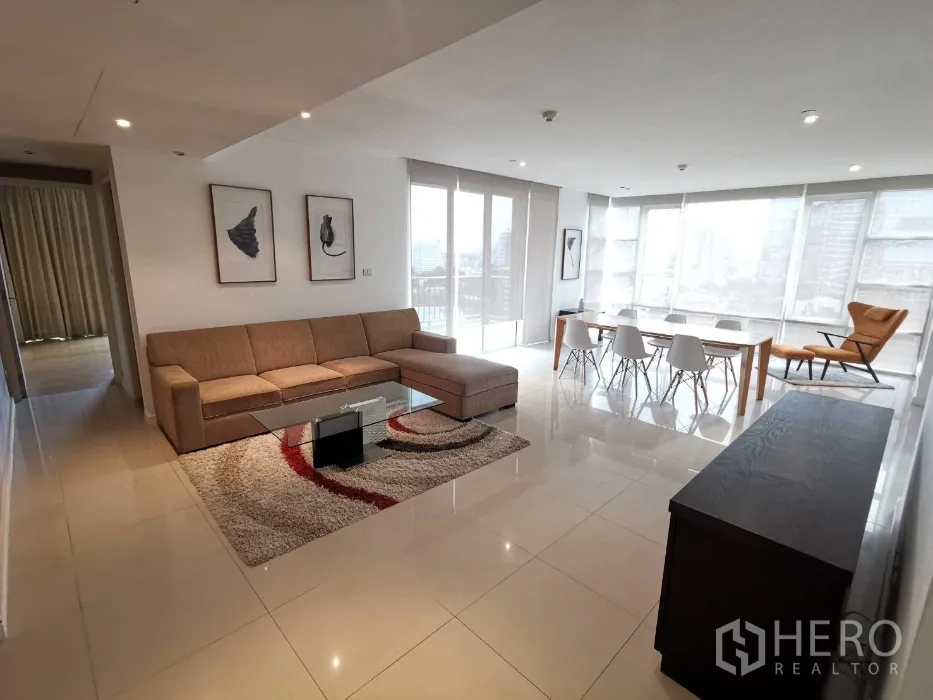 Condominium for rent in Watthana, Bangkok - Bright spacious living area with floor-to-ceiling windows, balcony, corner sofa, dining set for six, and glossy tiled floors.