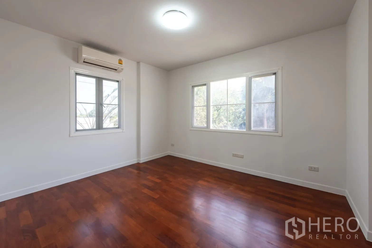 Detached House for sale in Bang Phli, Samut Prakan - Corner bedroom with multiple windows, wooden floor and air-conditioning unit.