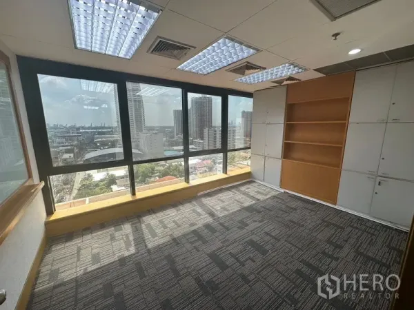 Office Space for rent in Khlong Toei, Bangkok - Private office with carpet tiles, built-in shelving and floor-to-ceiling windows.