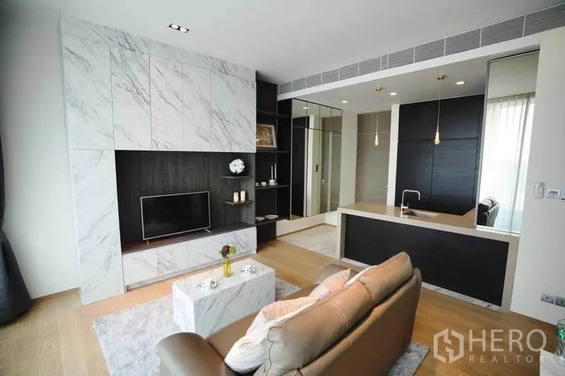 公寓 出租在Bang Rak, Bangkok - 从客厅望向厨房岛台，内置书架与电视背景墙。