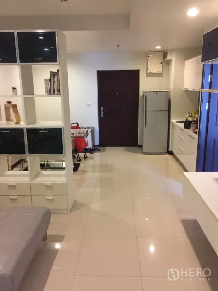 Condominium for rent in Watthana, Bangkok - Open-plan living area with shelving divider, dining nook, and entry beside the kitchenette.