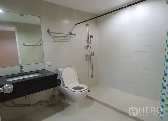 Condominium for rent in Huai Khwang, Bangkok - Second bathroom featuring a walk-in shower, toilet and black countertop vanity.