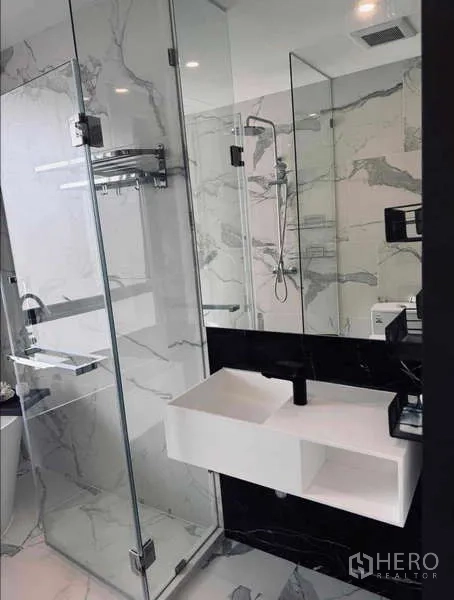 Condominium for rent in Khlong Toei, Bangkok - Vanity with rectangular sink beside glass shower in luxury bathroom.