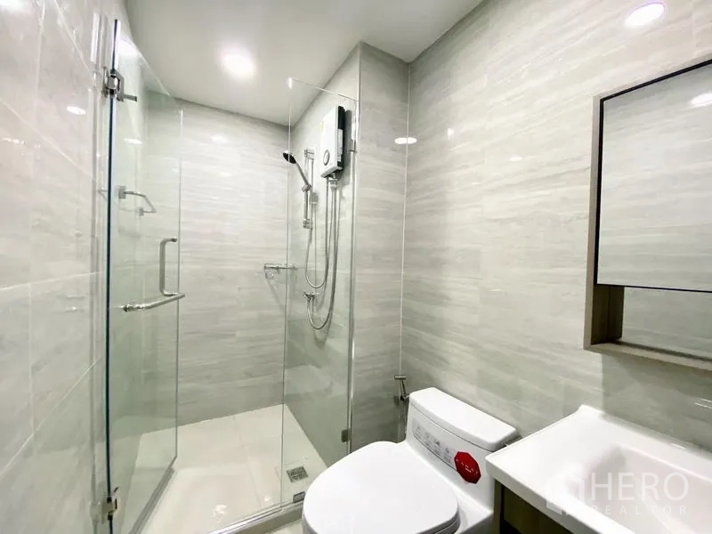 คอนโด ให้เช่า - ห้องน้ำที่สองมีตู้กระจกกั้นอาบน้ำ โถสุขภัณฑ์ และผนังลายหินอ่อนอ่อน