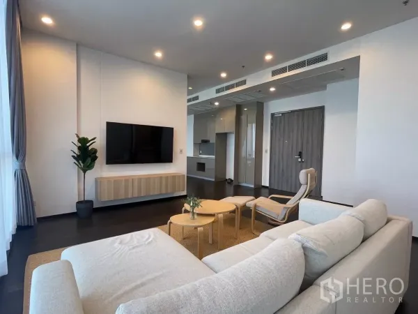 Condominium for rent in Phra Khanong, Bangkok - Open-plan lounge with TV wall, recessed lighting and access to a modern fitted kitchen.