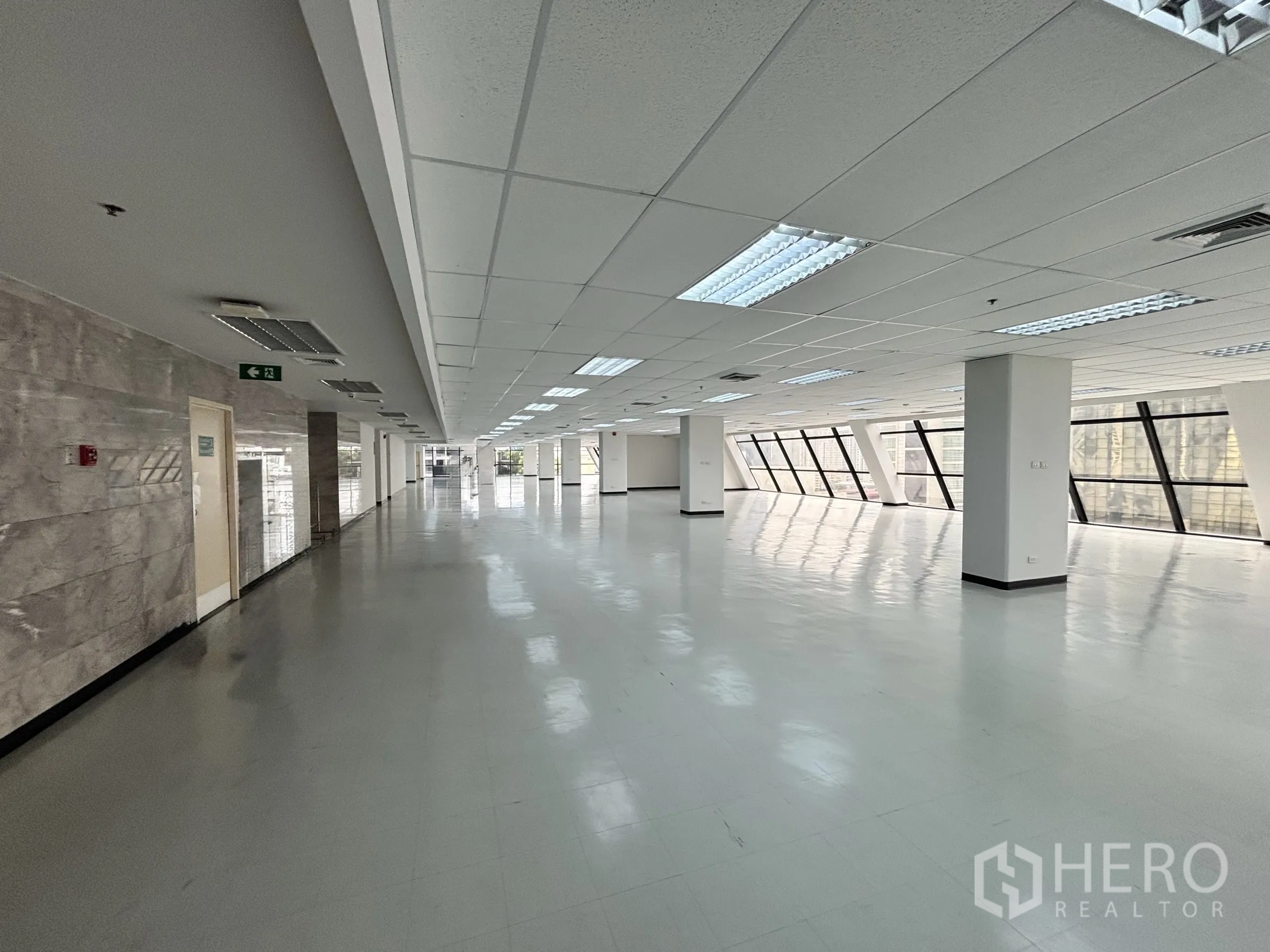 办公室 for rent in Ratchathewi, Bangkok - 走廊式区域带石材墙面装饰、吊顶照明与成排斜面玻璃。