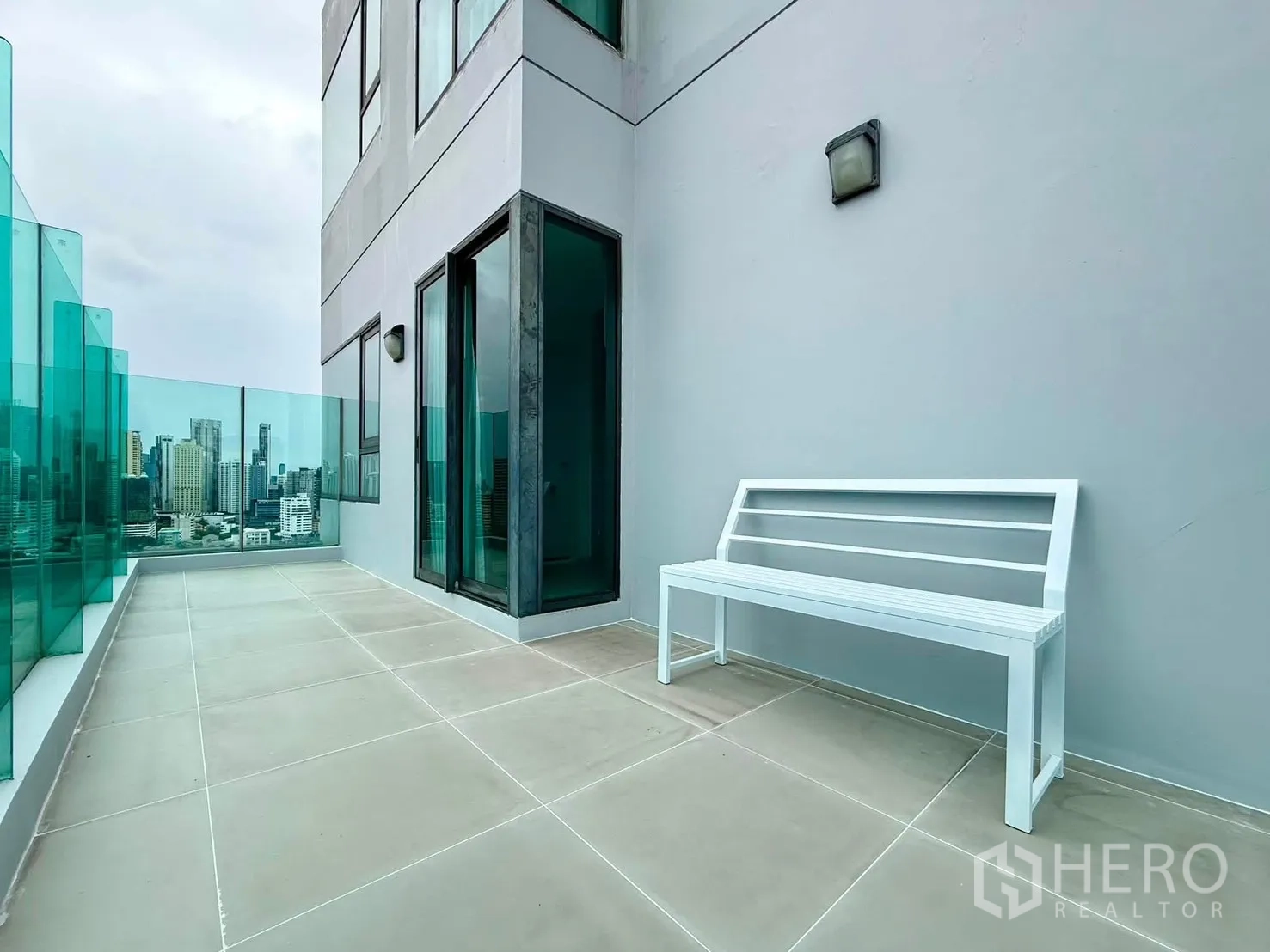 Condominium for rent in Khlong Toei, Bangkok - Large terrace with white bench seating and panoramic urban views.