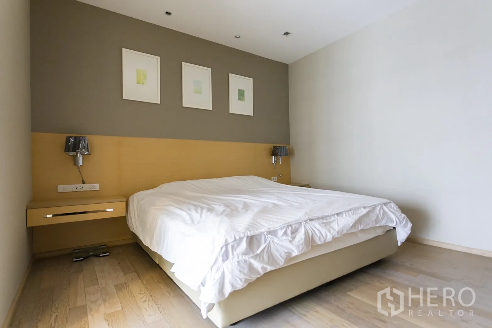 公寓 出租在Khlong Toei, Bangkok - 静谧卧室，特大床、木地板与壁挂床头灯。