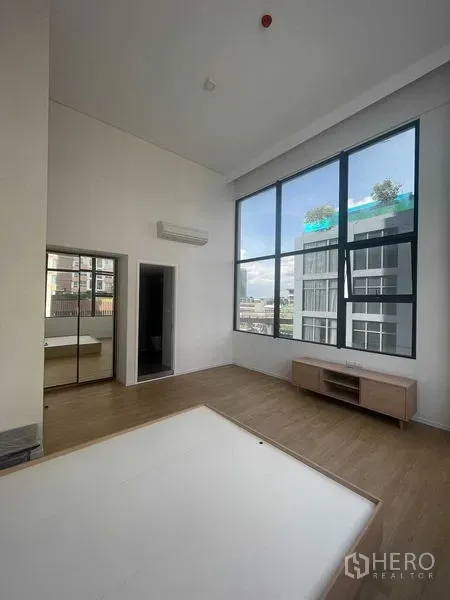 คอนโด ให้เช่าในKhlong Toei, Bangkok - ห้องนั่งเล่นเพดานสูง พร้อมหน้าต่างบานใหญ่ แอร์ และตู้วางทีวี