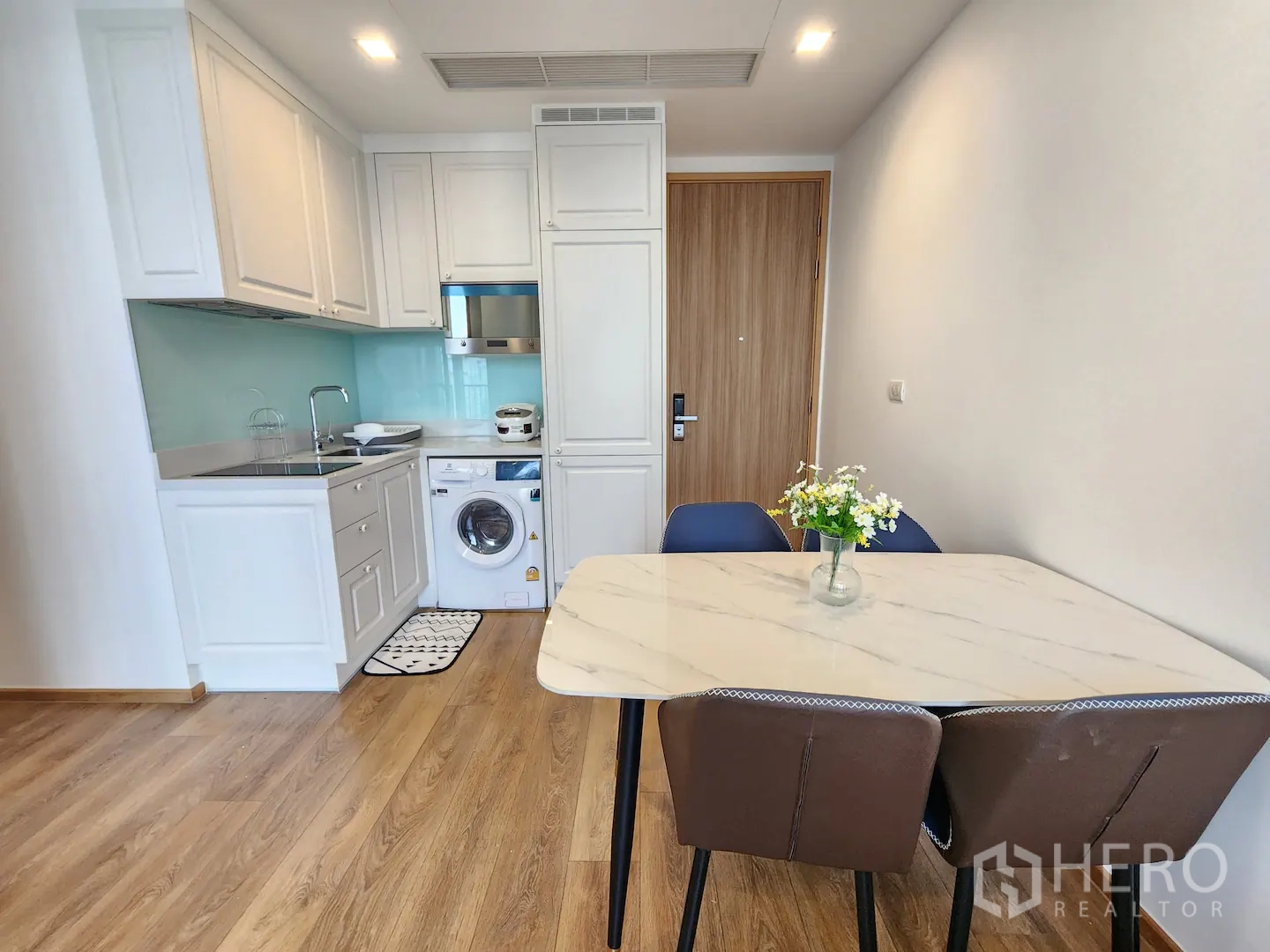 คอนโด for rent in Watthana, Bangkok - ครัวเปิดและมุมทานอาหาร ตู้บิวท์อินสีขาว เตาไฟฟ้า ไมโครเวฟ เครื่องซักผ้า และโต๊ะท็อปหินอ่อน