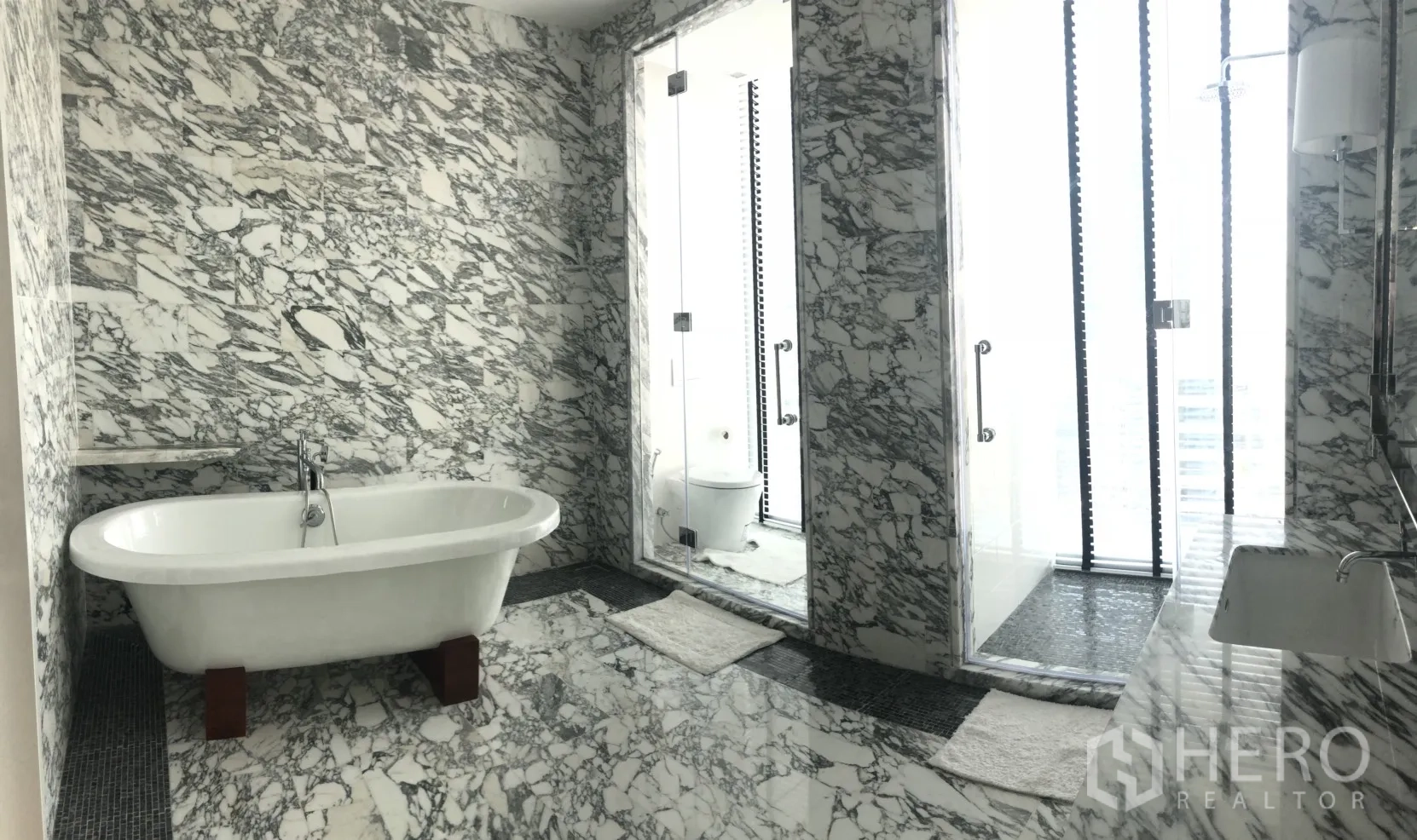 คอนโด ให้เช่าในBang Rak, Bangkok - ห้องน้ำหรูปูหินอ่อนโทนเทา‑ขาว พร้อมอ่างอาบน้ำเดี่ยวและห้องอาบน้ำกระจก