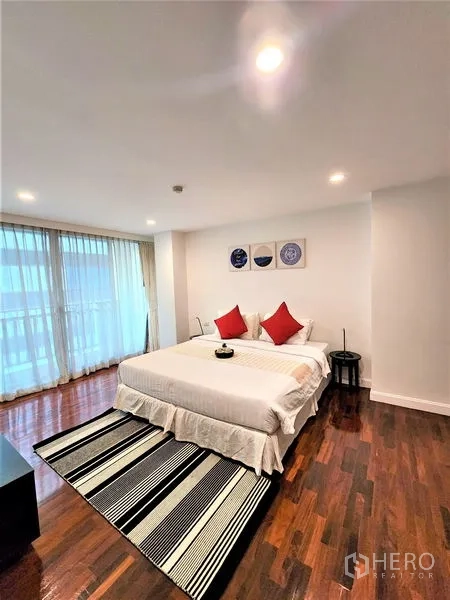 公寓 出租在Bang Rak, Bangkok - 卧室配大床、条纹地毯与落地窗。