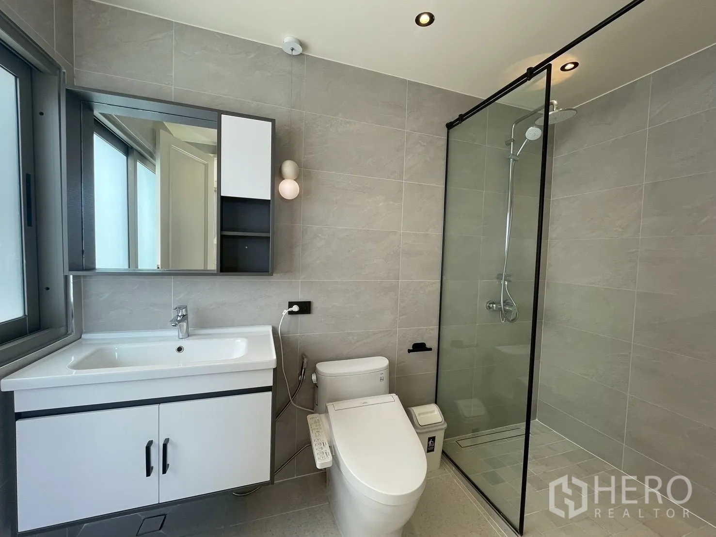 Condominium for sale in Watthana, Bangkok - Bright bathroom with window, vanity, toilet, and walk-in shower.