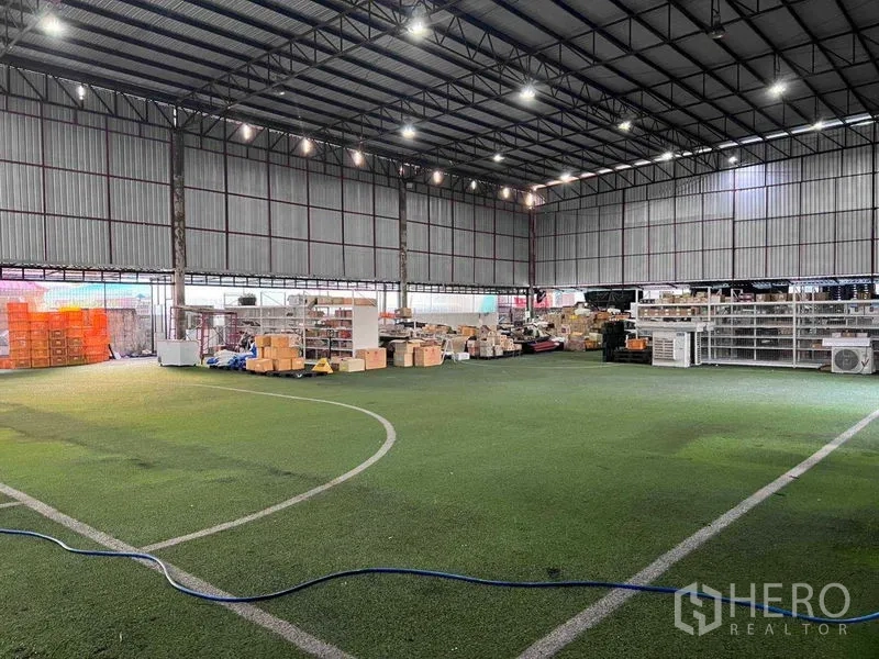 คลังสินค้า ให้เช่าในLat Phrao, Bangkok - ภายในโกดังโครงเหล็กเพดานสูง พื้นหญ้าเทียม ไฟ LED สว่าง พร้อมชั้นวางและกล่องสินค้า