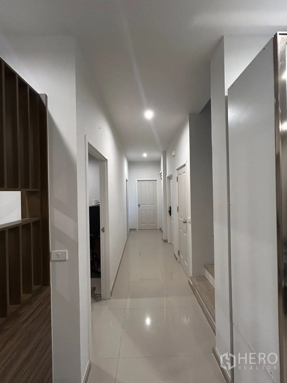 Detached House for rent in Khlong Sam Wa, Bangkok - Long hallway with recessed lighting leading to rooms and the staircase.