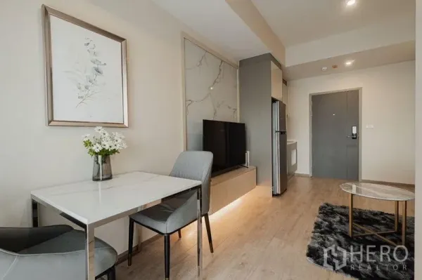 Condominium for rent - Compact dining nook beside a marble TV feature wall and entry hall in a modern Bangkok condominium.