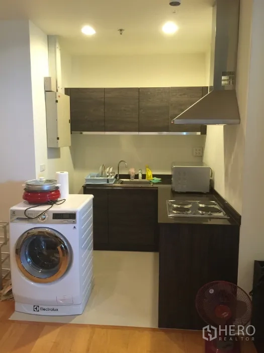 Condominium for rent in Bang Kho Laem, Bangkok - Compact kitchen with cabinets, electric stove, hood and front-loading washer.