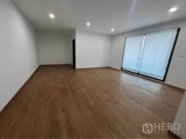 Home Office for rent in Bang Phli, Samut Prakan - Large empty room with wooden floors and sliding windows fitted with blinds.