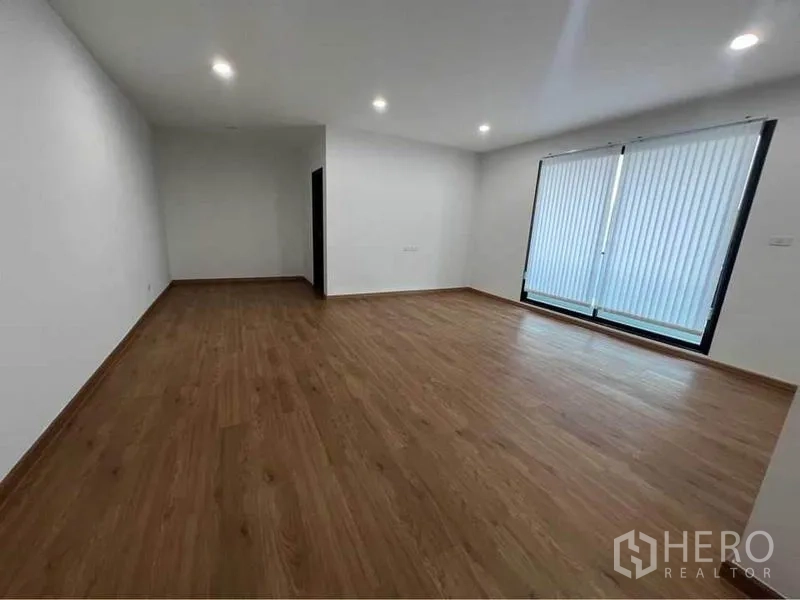 Home Office for rent in Bang Phli, Samut Prakan - Large empty room with wooden floors and sliding windows fitted with blinds.