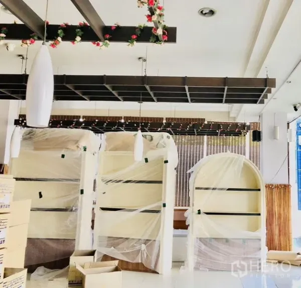 店屋 出租在Lat Phrao, Bangkok - 室内开放式展厅，吊灯与木质格栅天花，包装中的展示柜。