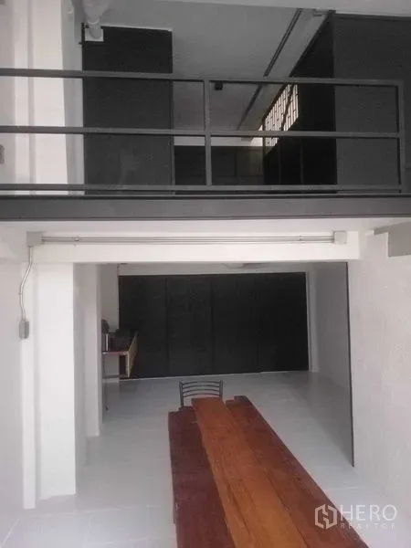 Shophouse for rent in Khlong Toei, Bangkok - Double-height space showing a mezzanine with metal railing above the open retail area.