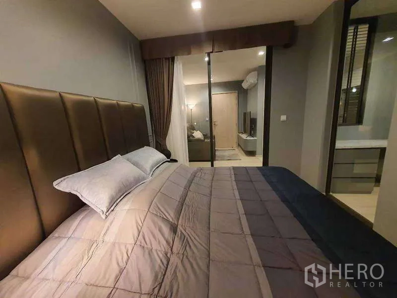 Condominium for rent - Cozy bedroom with padded headboard, drapes, and sliding glass wall facing the living area.