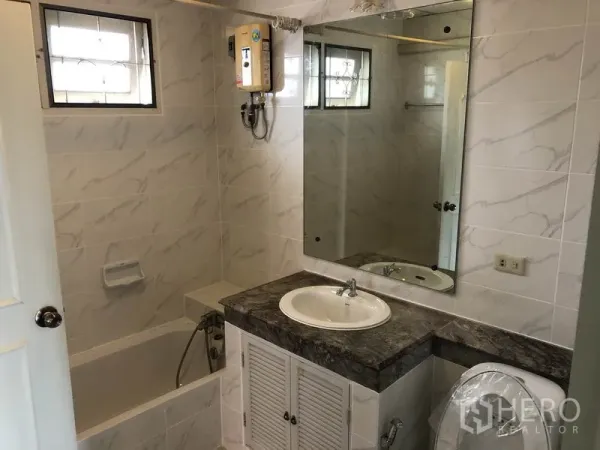 独立式住宅 出租 - 浴室带浴缸、热水器、大镜子与大理石纹瓷砖。