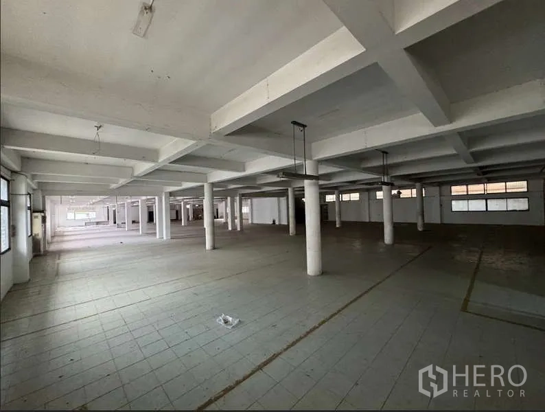 Home Office for sale in Bang Na, Bangkok - Expansive open-plan floor with concrete columns, tiled flooring and suspended lights.