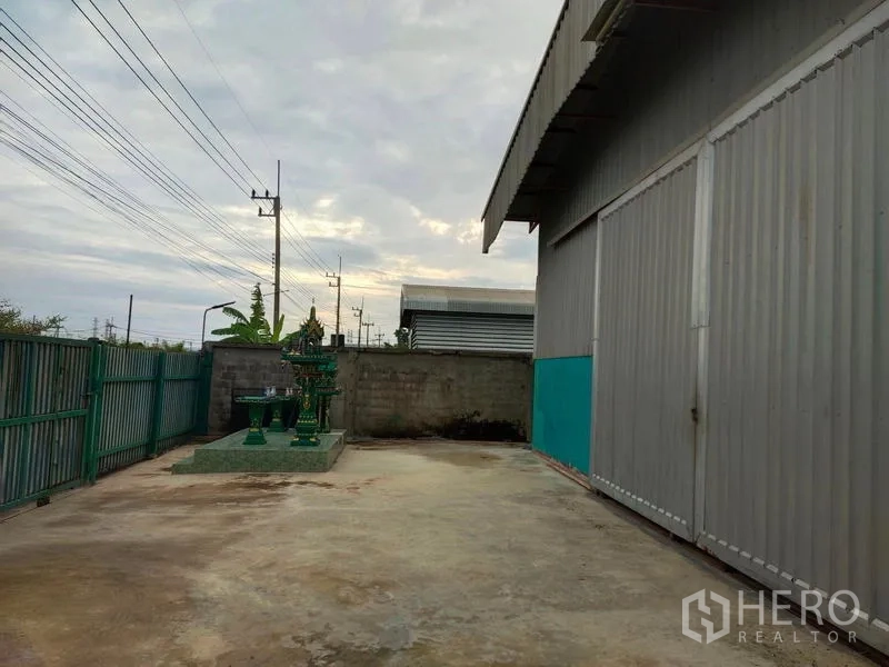 货栈 出售在Lam Luk Ka, Pathum Thani - 仓库旁混凝土院子，滑动大门与泰式神龛