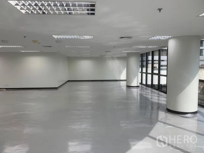 办公空间 出租在Bang Rak, Bangkok - 采光充足的办公区域，圆形立柱与低窗台，白色墙面待装修。