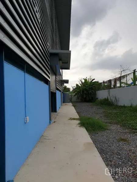 工厂 出售在Sai Noi, Nonthaburi - 厂房侧边混凝土人行道与碎石带，设小雨棚并有绿化。
