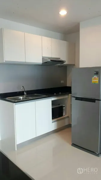 公寓 出租在Phaya Thai, Bangkok - 现代厨房，白色橱柜、水槽、炉灶与烟机、微波炉位及大冰箱。