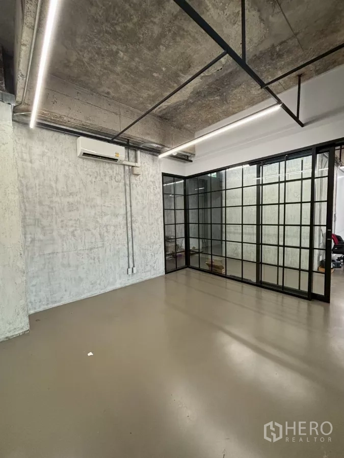 Office Space for rent in Watthana, Bangkok - Interior room looking toward the black-framed glass partitions under exposed ceilings.