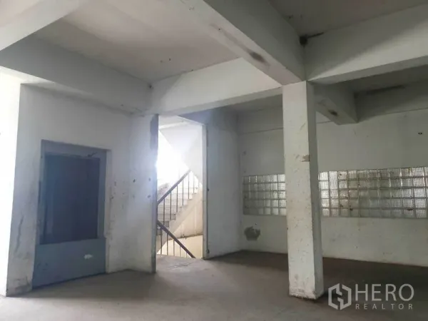 Shophouse for rent in Bang Bo, Samut Prakan - Ground floor corner showing pillars, stairwell and glass-block wall inside a shophouse.