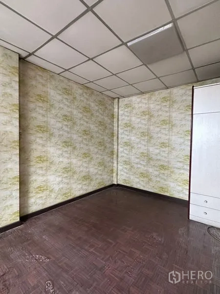 Shophouse for rent in Sathon, Bangkok - Compact room with patterned accent wall and parquet flooring.
