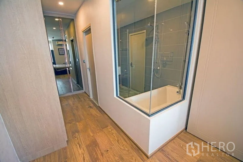 คอนโด ขายในRatchathewi, Bangkok - โถงทางเดินพื้นไม้พร้อมหน้าต่างกระจกบานใหญ่เห็นอ่างอาบน้ำและฝักบัว